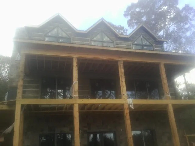Dormers and porch framing on a large log home under construction — Roof Coating work by our crew in Montpelier