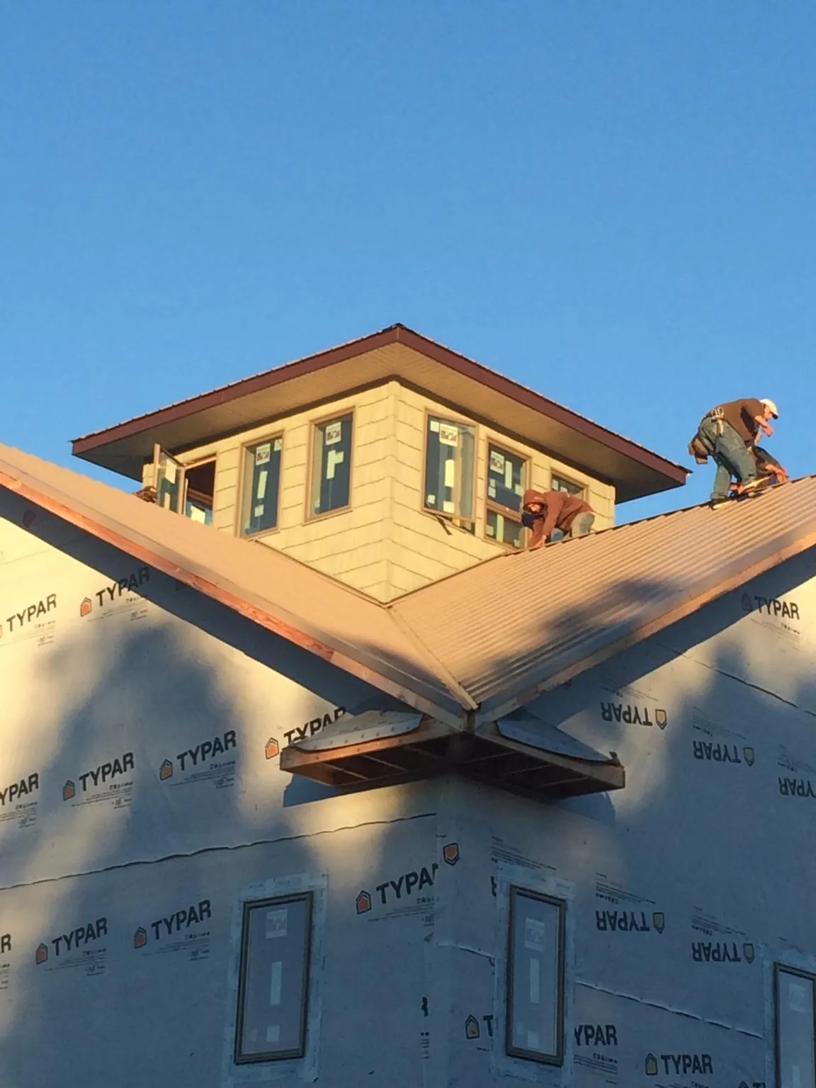 Roofers working around a rooftop cupola on a new metal roof at sunset — Roof Waterproofing in Montpelier by Roofing Brothers